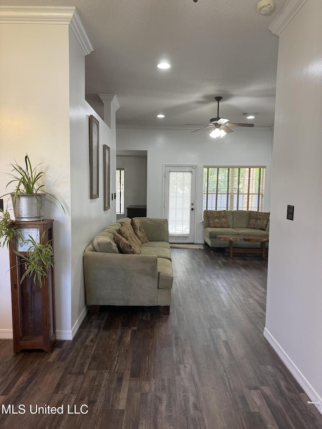 living area with a ceiling fan, baseboards, and dark wood-type flooring
