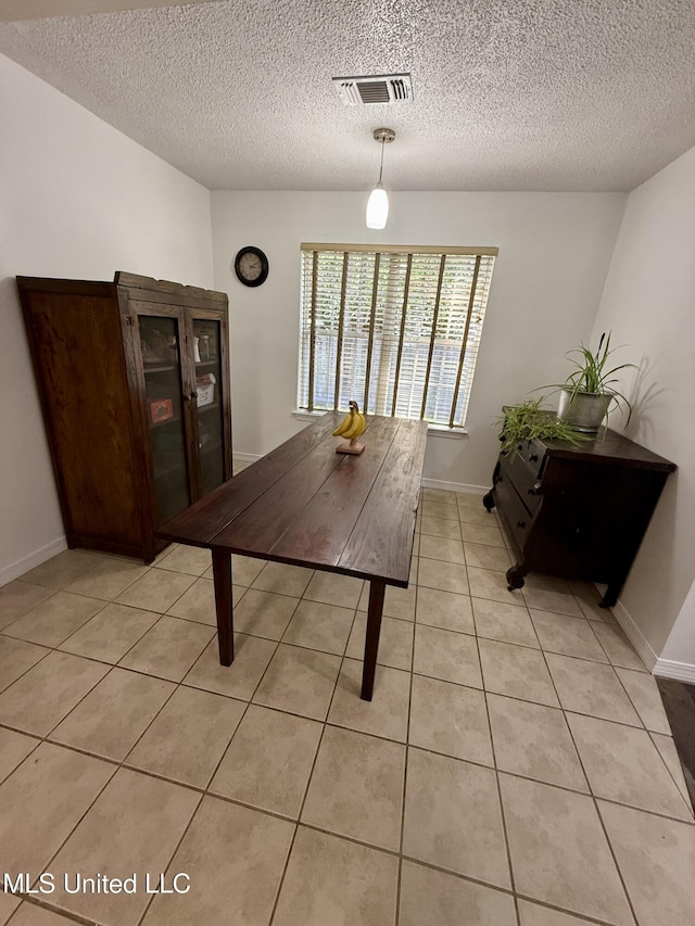 dining space with light tile patterned floors, baseboards, a textured ceiling, and visible vents