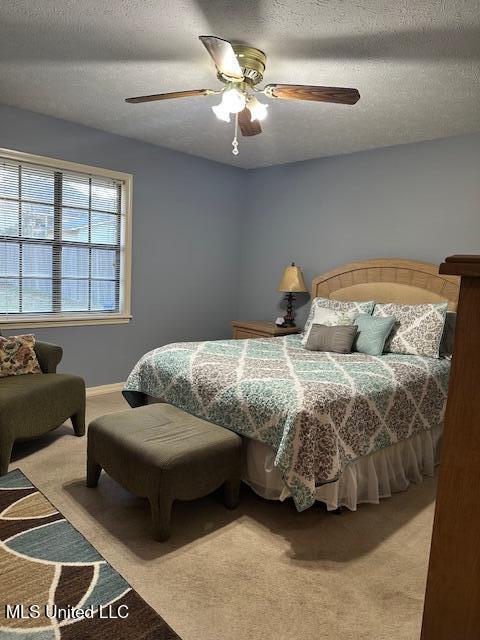 carpeted bedroom featuring a ceiling fan and a textured ceiling