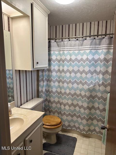 bathroom with wallpapered walls, toilet, a shower with shower curtain, vanity, and a textured ceiling