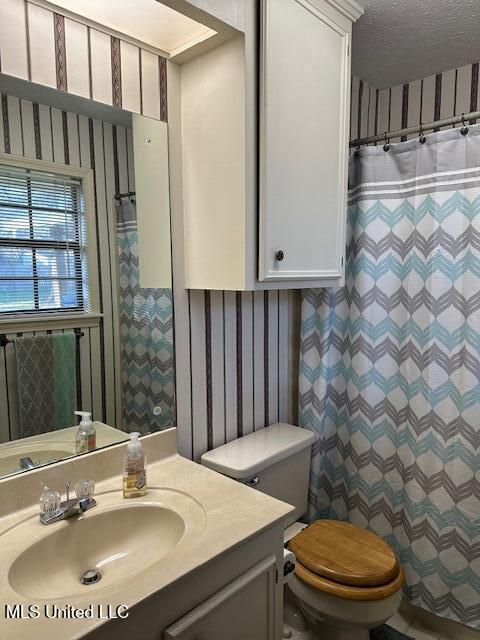 bathroom featuring toilet, a textured ceiling, a shower with shower curtain, wallpapered walls, and vanity