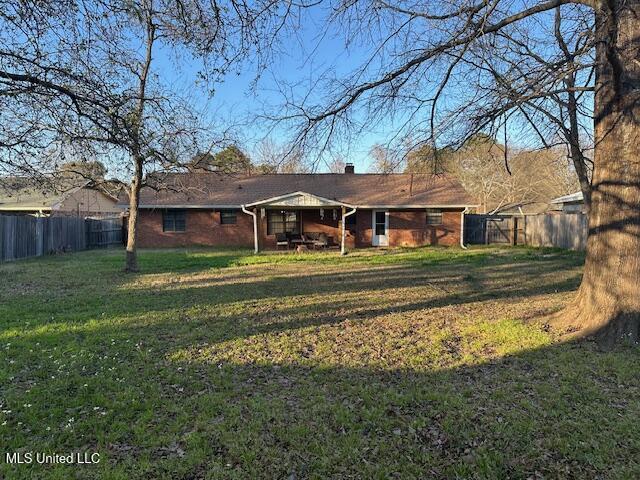 rear view of house featuring a yard, a fenced backyard, and brick siding