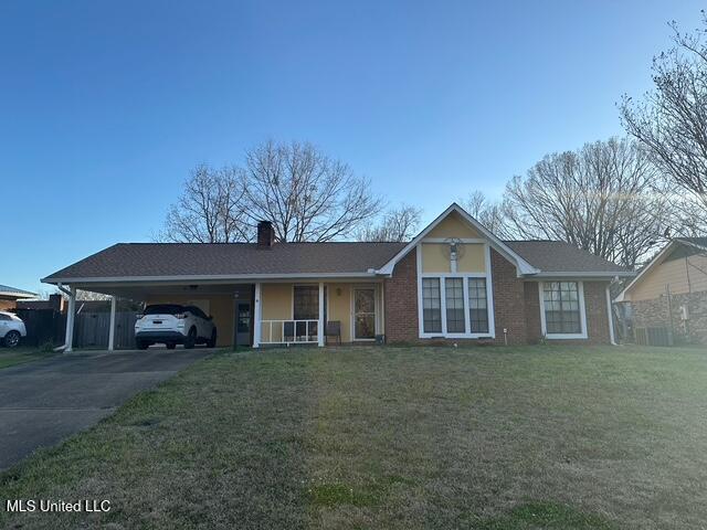 single story home with brick siding, an attached carport, a front lawn, a chimney, and driveway