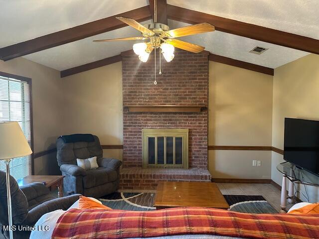 living area featuring visible vents, baseboards, lofted ceiling with beams, a fireplace, and tile patterned floors