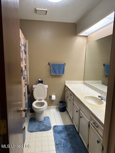 bathroom with vanity, toilet, tile patterned flooring, and a textured ceiling