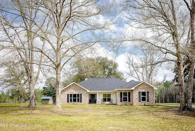 view of front of home featuring brick siding, a front yard, and roof with shingles