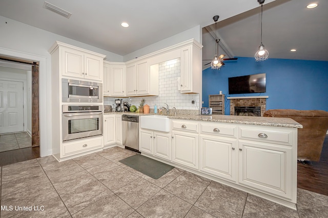 kitchen with visible vents, open floor plan, a peninsula, stainless steel appliances, and a sink