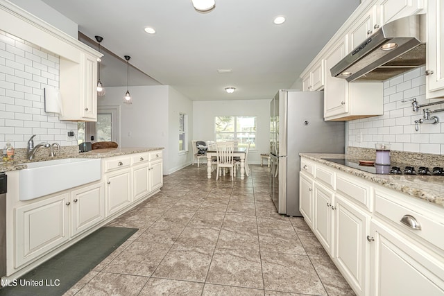 kitchen with under cabinet range hood, decorative backsplash, hanging light fixtures, stainless steel appliances, and a sink