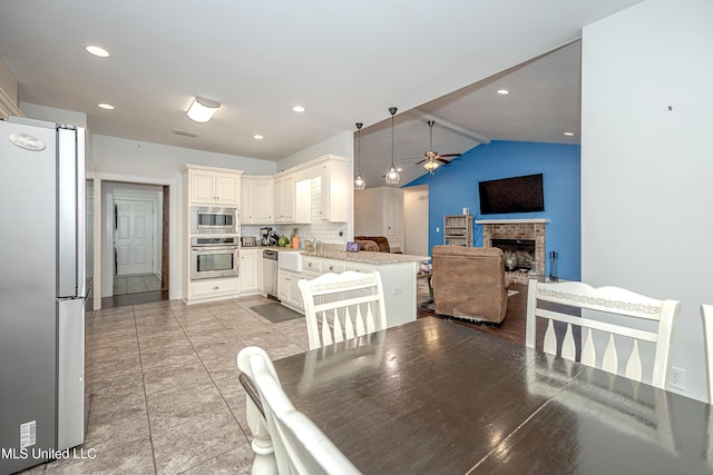 dining area featuring vaulted ceiling, a brick fireplace, recessed lighting, and a ceiling fan