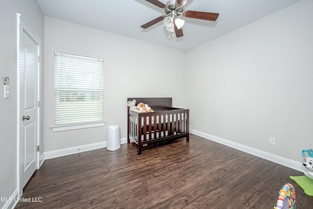 bedroom featuring ceiling fan, baseboards, a nursery area, and wood finished floors