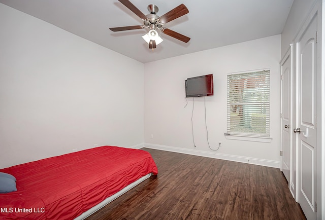 unfurnished bedroom featuring dark wood-style floors, a ceiling fan, and baseboards