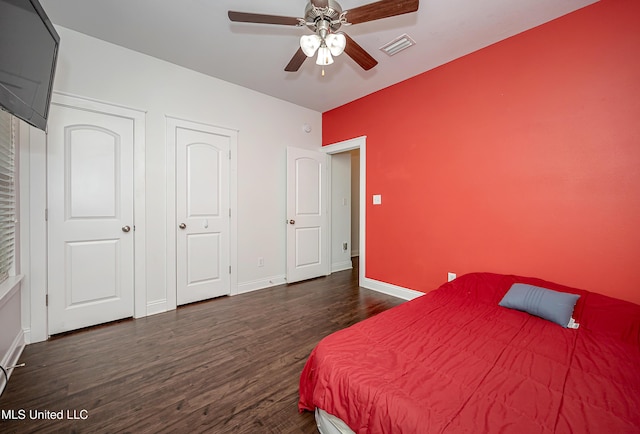 bedroom with dark wood finished floors, visible vents, ceiling fan, and baseboards