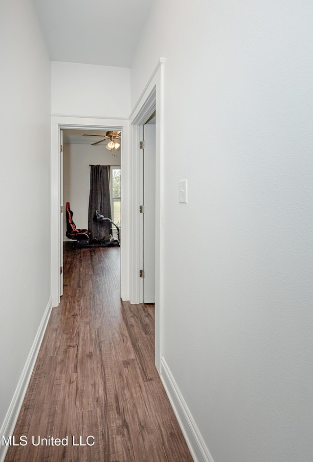 corridor with baseboards and wood finished floors