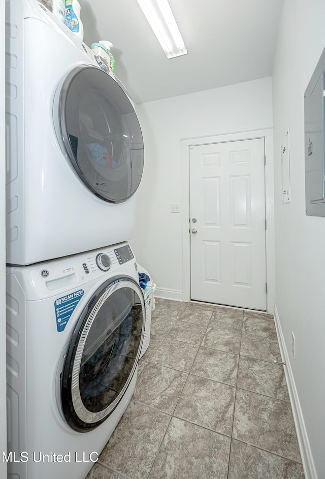 laundry room featuring baseboards, stacked washer and clothes dryer, and laundry area