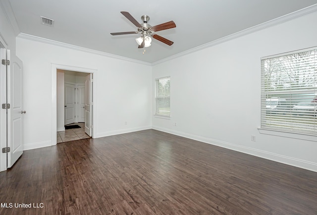 spare room with visible vents, ornamental molding, dark wood finished floors, baseboards, and ceiling fan