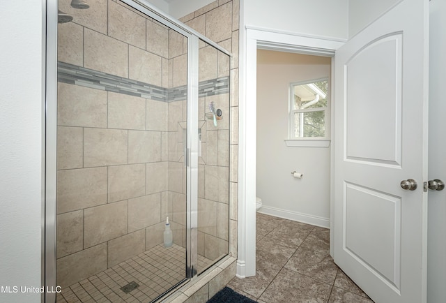 full bath featuring baseboards, toilet, a stall shower, and tile patterned flooring