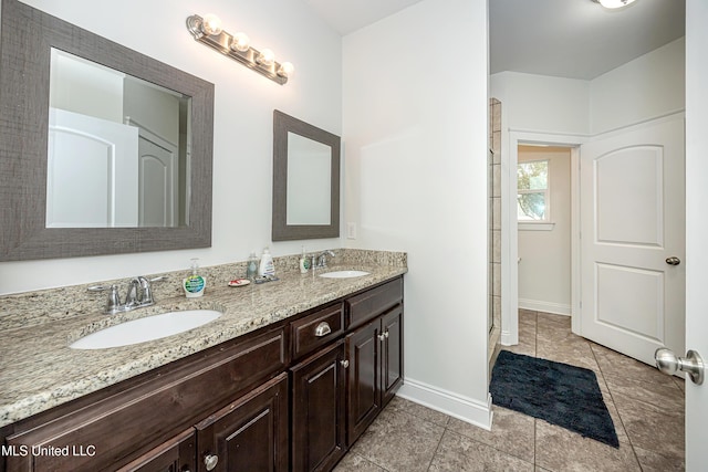 full bathroom with a sink, baseboards, double vanity, and tile patterned floors