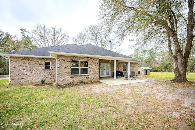 back of property featuring a patio area, a lawn, a shingled roof, and an outbuilding