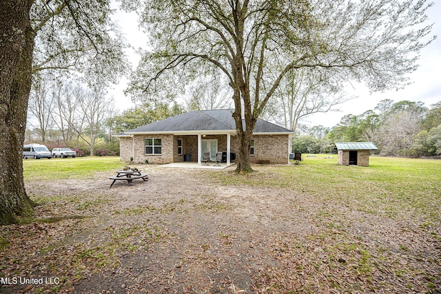 rear view of house with a patio, a lawn, a fire pit, and an outdoor structure