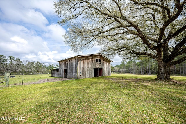 view of barn featuring a yard and fence