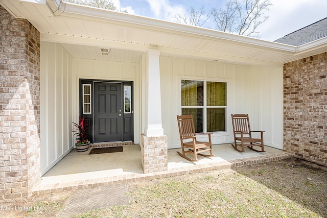 property entrance featuring brick siding, a porch, and board and batten siding