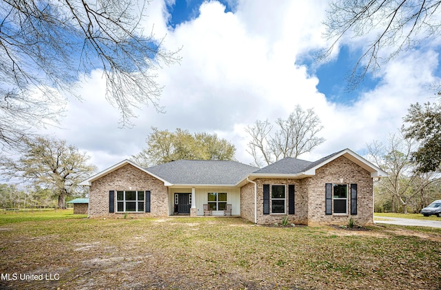 single story home featuring a front yard, brick siding, and roof with shingles