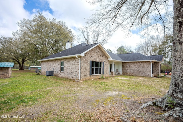 back of property with brick siding, a lawn, cooling unit, and a chimney