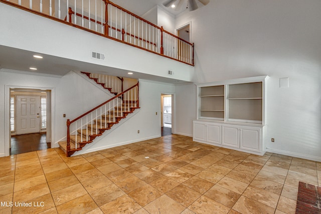 unfurnished living room featuring a high ceiling, crown molding, built in features, and ceiling fan