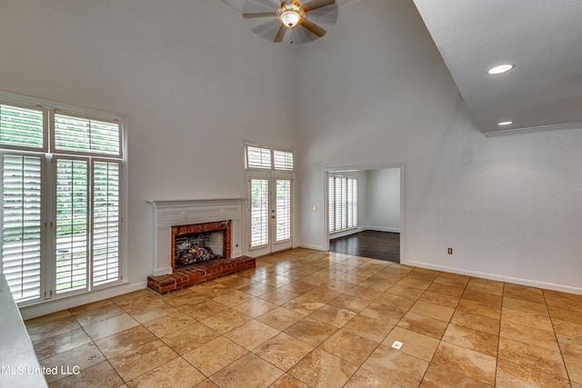 unfurnished living room featuring ceiling fan, a towering ceiling, light tile patterned flooring, and a fireplace