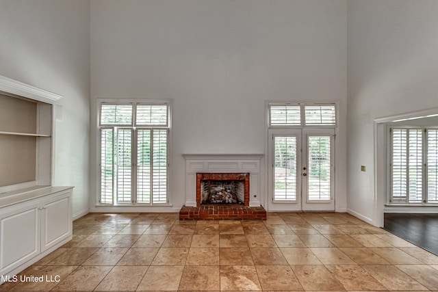 unfurnished living room featuring a high ceiling, a fireplace, and plenty of natural light