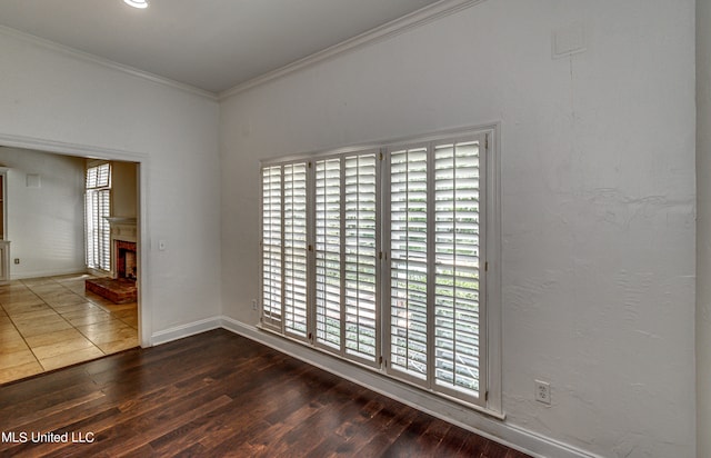 spare room featuring crown molding, dark hardwood / wood-style flooring, and a brick fireplace