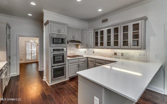 kitchen featuring kitchen peninsula, stainless steel appliances, crown molding, and dark hardwood / wood-style flooring