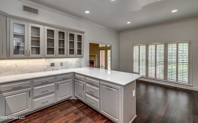 kitchen with decorative backsplash, dark hardwood / wood-style flooring, kitchen peninsula, and gray cabinets