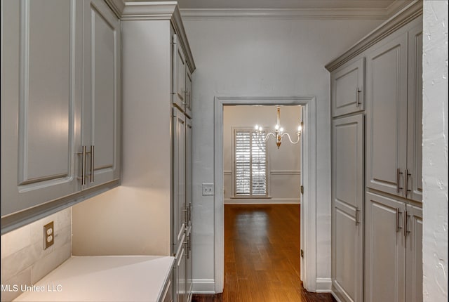 corridor featuring ornamental molding, dark wood-type flooring, and a chandelier