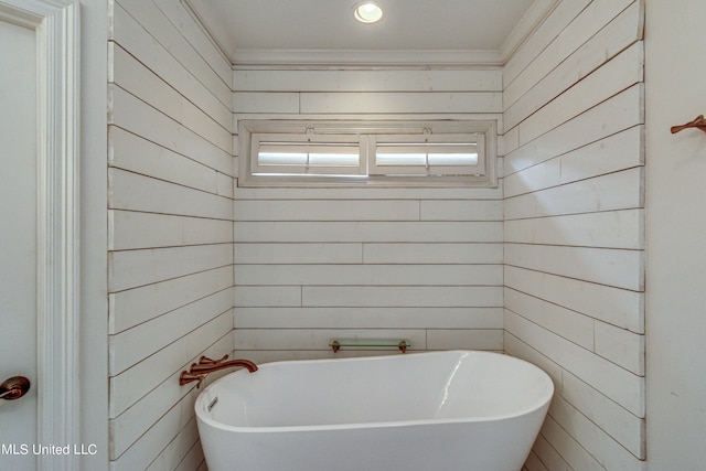 bathroom featuring ornamental molding, wood walls, and a tub