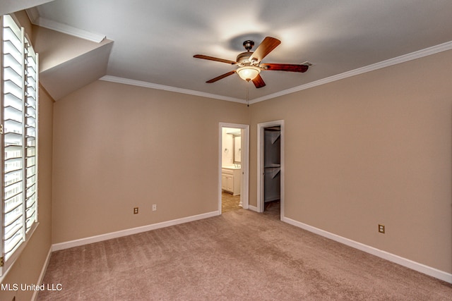 unfurnished bedroom featuring a walk in closet, a closet, light carpet, ceiling fan, and ornamental molding