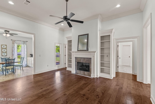 125 Rhodes Ln, Canton, MS 39046 - unfurnished living room with a ceiling fan, wood finished floors, crown molding, a tiled fireplace, and built in features
