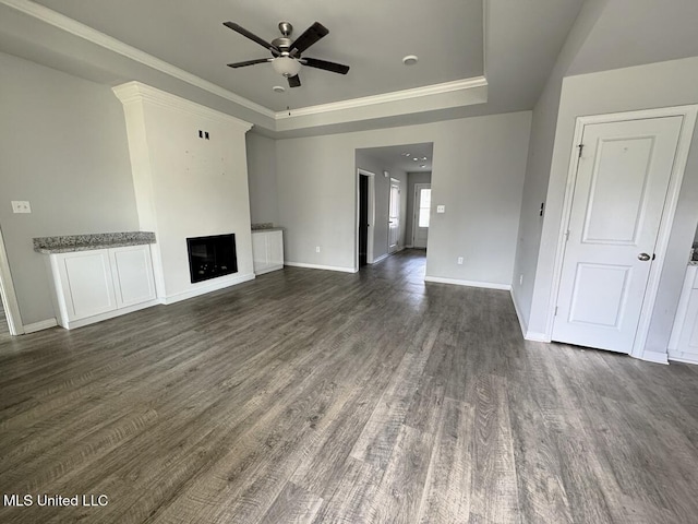 unfurnished living room with a raised ceiling, crown molding, ceiling fan, and dark hardwood / wood-style floors