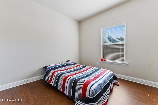 bedroom with dark wood finished floors and baseboards