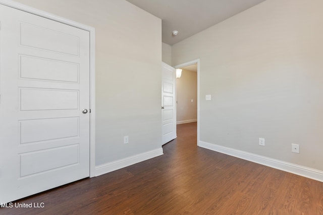 empty room with dark wood-style flooring and baseboards