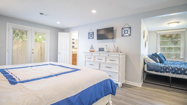 bedroom featuring connected bathroom, access to exterior, a textured ceiling, and light wood-type flooring