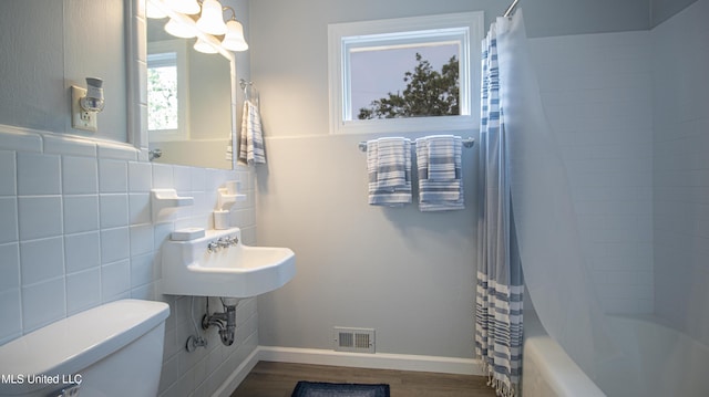 bathroom featuring wood-type flooring, toilet, and shower / bath combo