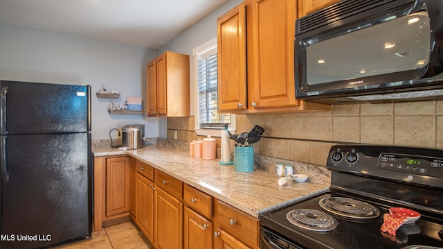 kitchen with light stone counters, tasteful backsplash, black appliances, and light tile patterned flooring