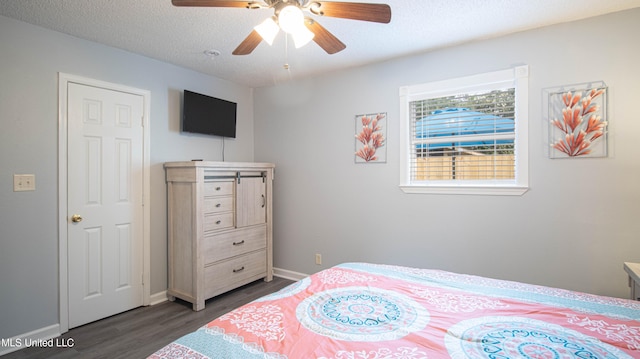 bedroom with dark hardwood / wood-style floors, a textured ceiling, and ceiling fan