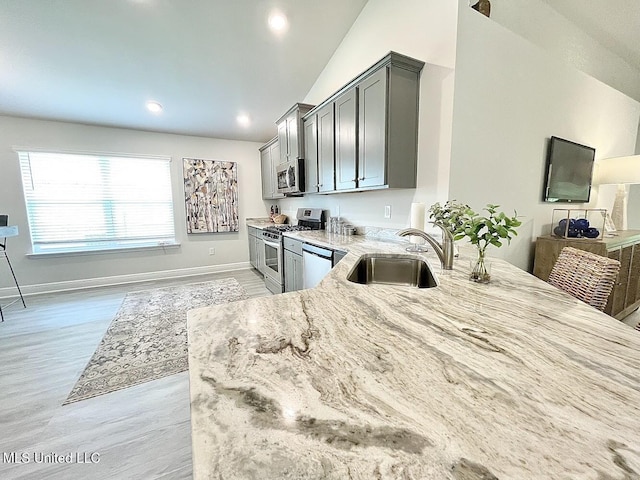 14007 Plantation Oaks Dr, Gulfport, MS 39503 - kitchen with appliances with stainless steel finishes, light stone countertops, a sink, light wood finished floors, and baseboards