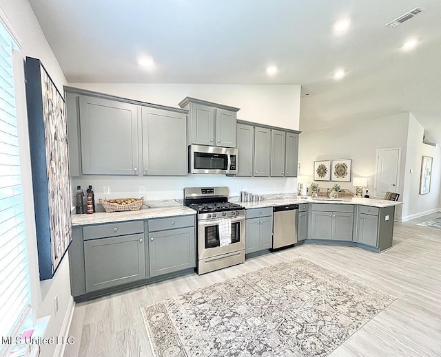 14007 Plantation Oaks Dr, Gulfport, MS 39503 - kitchen featuring appliances with stainless steel finishes, gray cabinets, vaulted ceiling, a sink, and light countertops