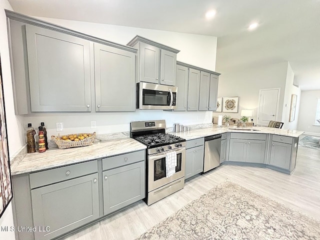 14007 Plantation Oaks Dr, Gulfport, MS 39503 - kitchen with stainless steel appliances, gray cabinets, light wood finished floors, a peninsula, and light stone countertops