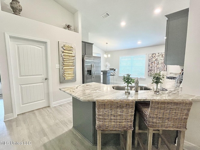 14007 Plantation Oaks Dr, Gulfport, MS 39503 - kitchen featuring stainless steel refrigerator with ice dispenser, a sink, a peninsula, light stone countertops, and lofted ceiling