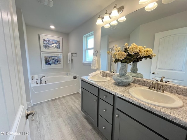 14007 Plantation Oaks Dr, Gulfport, MS 39503 - bathroom featuring double vanity, a garden tub, and wood finished floors
