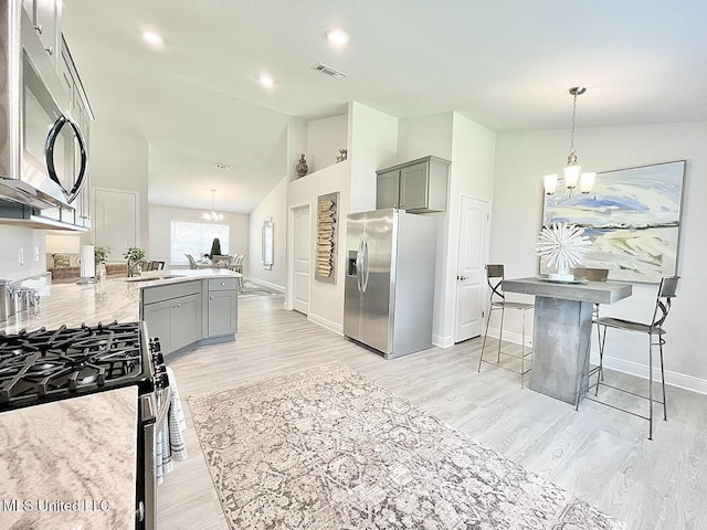14007 Plantation Oaks Dr, Gulfport, MS 39503 - kitchen with stainless steel appliances, gray cabinetry, a chandelier, light wood-style floors, and lofted ceiling